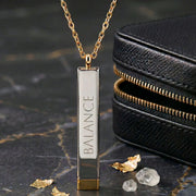 LUMA Hidden Message bar necklace engraved BALANCE, styled with a leather pouch and gold flakes