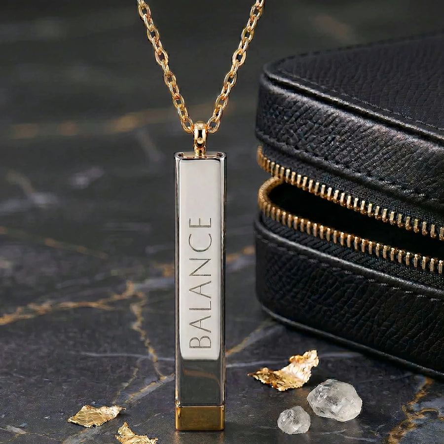 LUMA Hidden Message bar necklace engraved BALANCE, styled with a leather pouch and gold flakes
