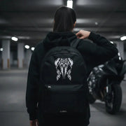 Woman adjusting the LUMA Tribal Ram backpack strap, motorcycle visible in background