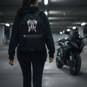 Woman walking away wearing the LUMA Tribal Ram backpack, motorcycle in a parking garage