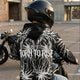Motorcyclist wearing the LUMA Born to Rise hoodie, back graphic visible, parking lot at sunset