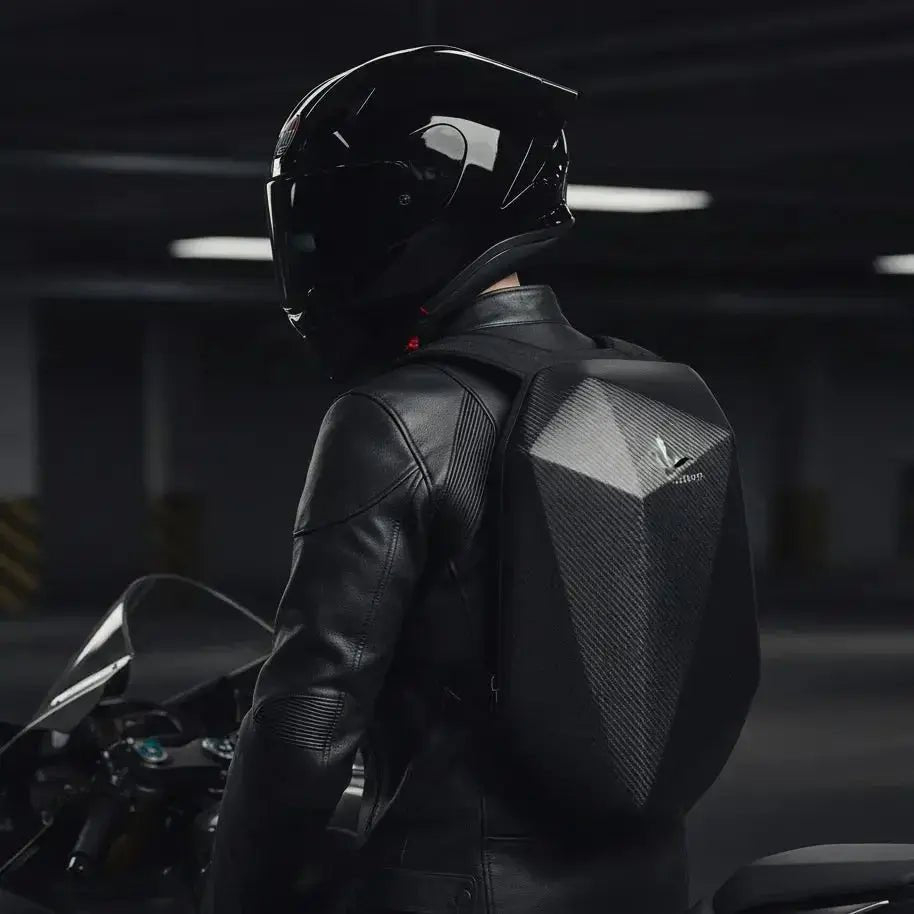 Motorcyclist in leather jacket and helmet wearing the LUMA CarbonRide waterproof backpack, rear view