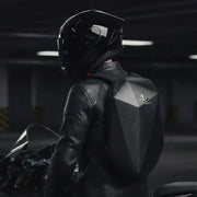 Motorcyclist in leather jacket and helmet wearing the LUMA CarbonRide waterproof backpack, rear view