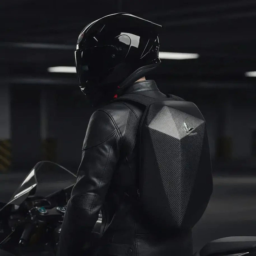 Motorcyclist in leather jacket and helmet wearing the LUMA CarbonRide waterproof backpack, rear view