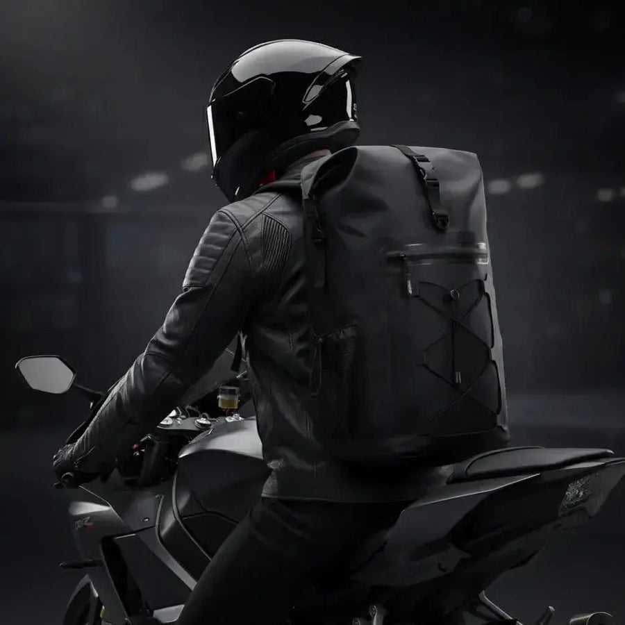 Motorcyclist riding a sportbike wearing the black LUMA AquaRider waterproof backpack, rear view