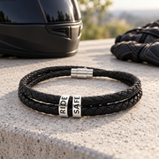 Engraved leather biker bracelet with RIDE SAFE beads beside a black motorcycle helmet and riding gloves