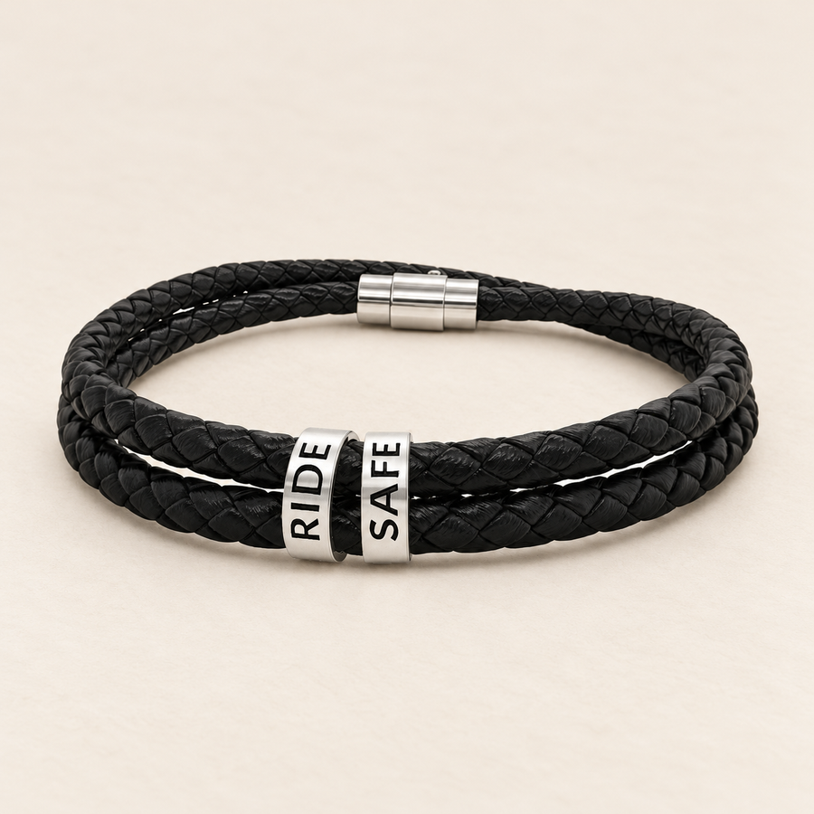 Black braided leather bracelet with magnetic clasp and two engraved steel beads RIDE SAFE on a light background