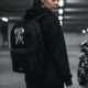 Woman wearing the LUMA Tribal Ram backpack in a parking garage, tribal skull graphic visible