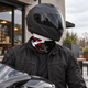Rider in a black full-face helmet and jacket wearing a lightweight UPF 50+ motorcycle neck gaiter in red and black