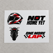 Four motorcycle vinyl stickers on a white sheet on a grey surface: helmet, Not Home Yet, sportbike, One More Lap (mockup)