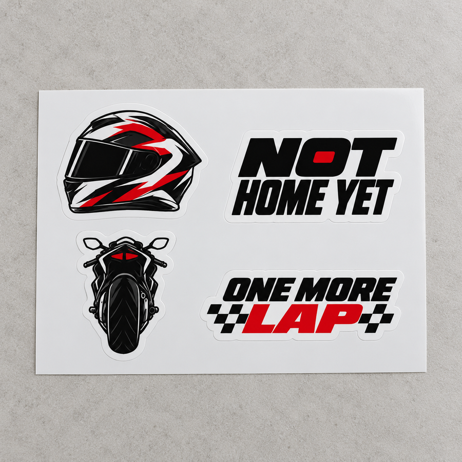 Four motorcycle vinyl stickers on a white sheet on a grey surface: helmet, Not Home Yet, sportbike, One More Lap (mockup)