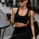 Woman sitting at a cafe wearing the LUMA Square Neck Seamless set in black, holding coffee