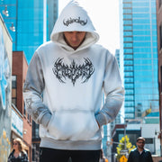 Man wearing the LUMA Gothic Washed hoodie in white, front graphic and hood text, city street