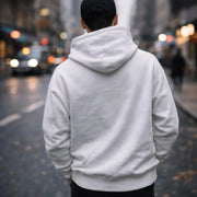 Man walking a city street wearing the LUMA White Velvet oversized hoodie, back view