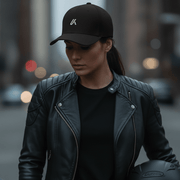 Woman wearing the LUMA Rider snapback cap and leather motorcycle jacket, holding a helmet